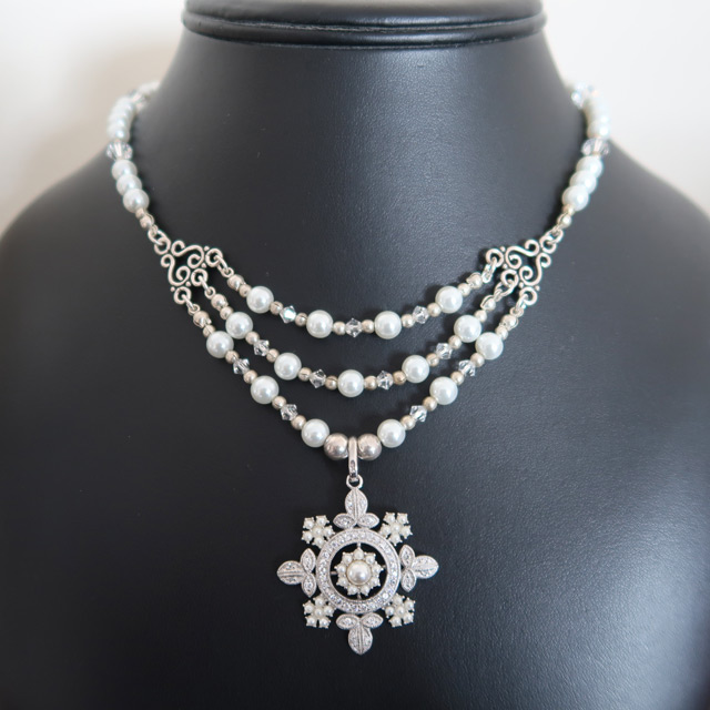 A white glass pearl and Swarovski crystal necklace with a snowflake pendant